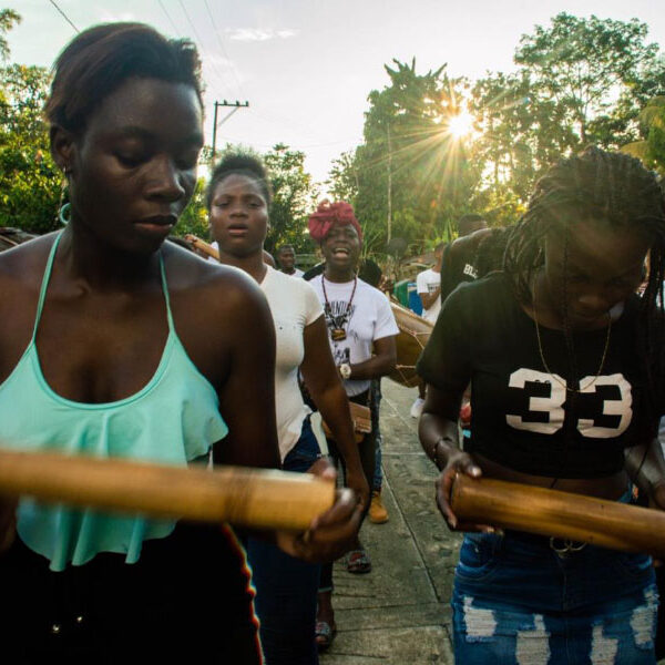 A group of black youth are marching outside and playing musical instruments.